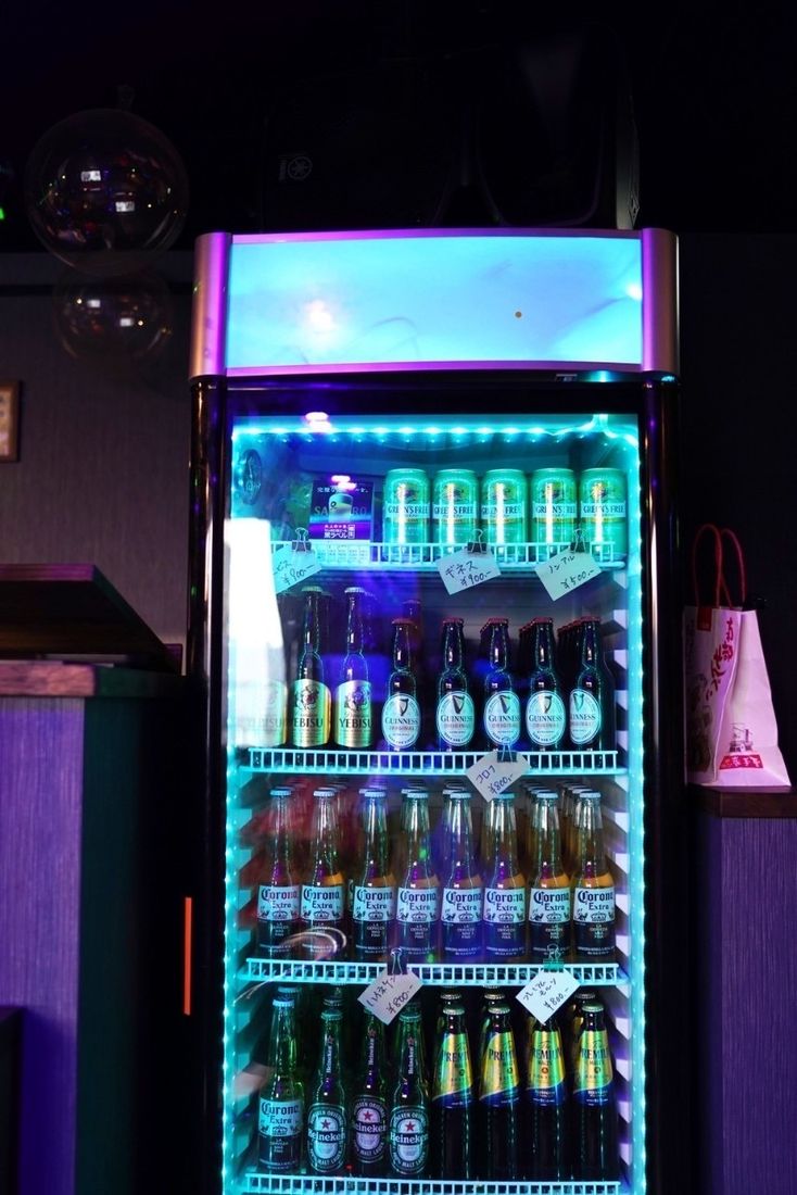 ネオンに照らされたドリンク冷蔵庫に並ぶボトルビール